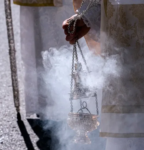 Monaguillo balanceando un incensario de plata desprendiendo humo de incienso durante una procesión de Semana Santa en Cuevas del Almanzora